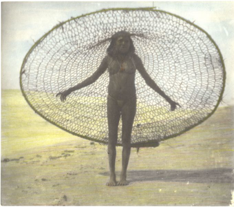 229018 Vrouw van de Marind-anim poseert met een visnet op haar hoofd op het strand nabij Okaba (Indonesië)